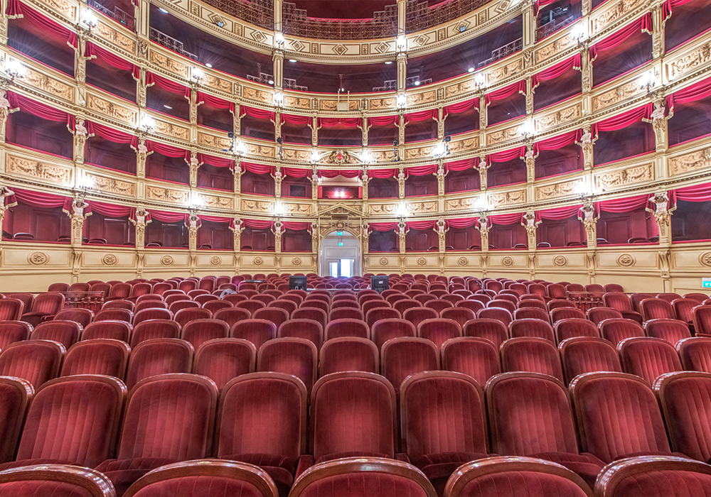 Interior of Teatro Verdi featuring classic red velvet theater seats